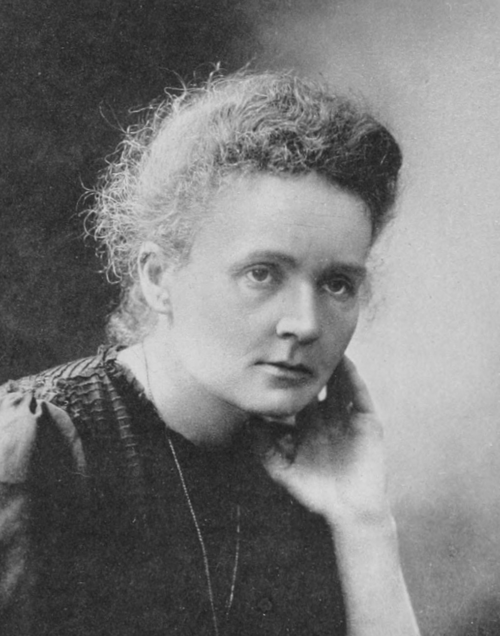 Black and white photograph of Marie Curie, resting her chin on her hand